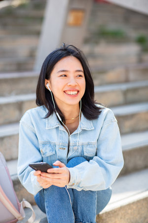 Portrait smiling young woman listening to music with phone and earphonesの写真素材