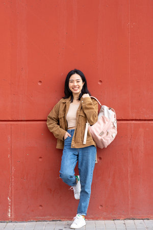 Portrait young woman smiling with bag by wallの写真素材