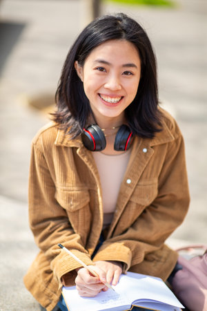 Portrait young woman sitting outside with pen and bookの写真素材