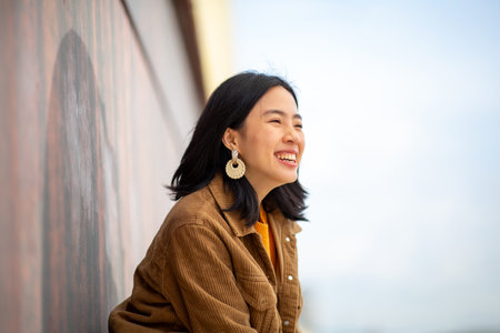 Portrait young asian woman smiling by wall outsideの写真素材