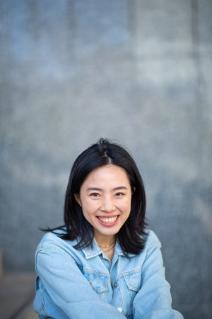 Portrait smiling young chinese woman against blurry backgroundの写真素材