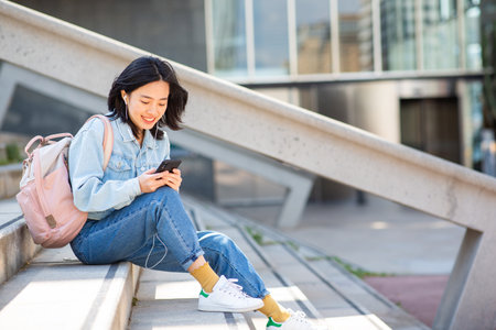 Portrait smiling young woman sitting with mobile phoneの写真素材