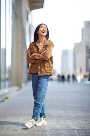 Full body portrait smiling young asian woman in cityの写真素材