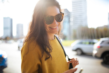 Close up portrait of happy young woman with sunglasses walking outside in the cityの写真素材