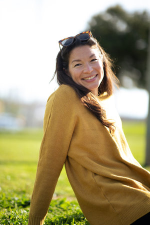 Portrait of beautiful young asian woman sitting outside and smilingの写真素材
