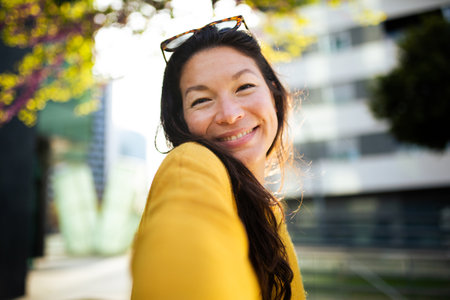 Close-up portrait of attractive woman looking at camera and smiling standing outside in city
