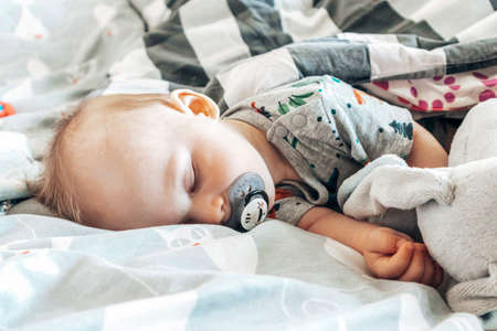 Cute little baby boy sleeping in bed with pacifier. Newborn child lying on the bed.の写真素材