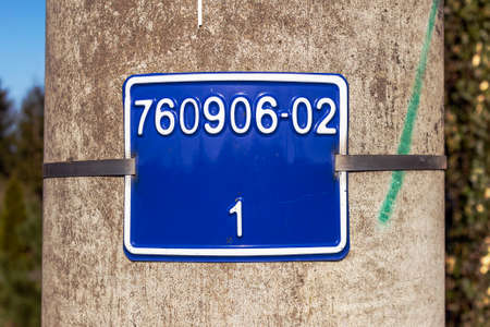 Metal plate with numbers on a concrete pole.の写真素材