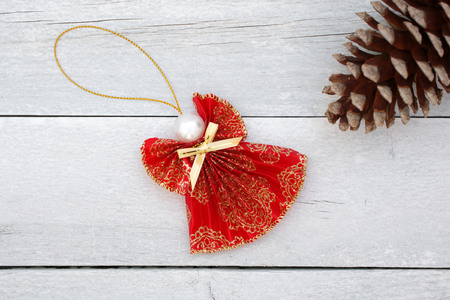 Christmas decoration of reddish angel and pinecone on old wooden background.の写真素材