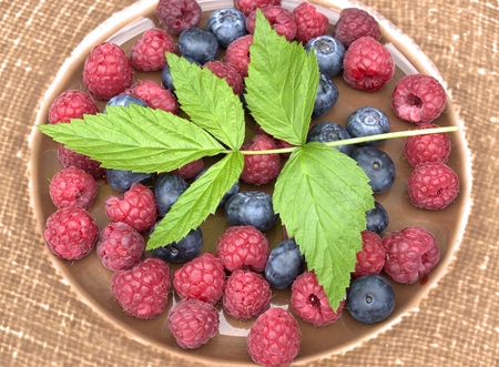Raspberries and berries on porcelain plate.