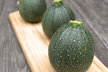 Round courgette on cutting board and on wooden background.の写真素材