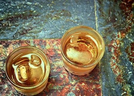 Alcohol, taste and drink concept-two glasses of whiskey on a old stone background.の写真素材