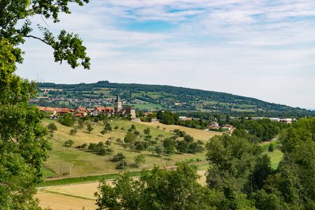 Picturesque landscape view of meadows, pastures, fields, trees, town of Brens and white clouds in the blue sky.Department of Haute-Savoie, region of Auvergne-Rhone-Alpes in France.の写真素材