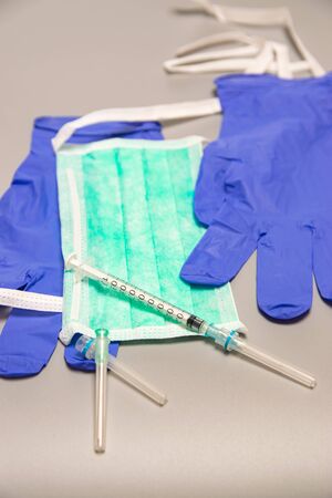 Health, protection, treatment and medical concept: Medical syringe with needles, mask and medical gloves on gray background.の写真素材