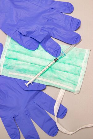 Health, protection, treatment and medical concept: Medical syringe with needles, mask and medical gloves on gray background.の写真素材
