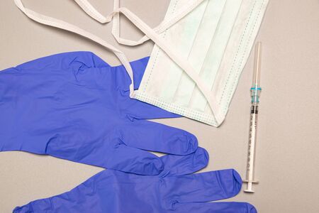 Health, protection, treatment and medical concept: Medical syringe with needles, mask and medical gloves on gray background.の写真素材