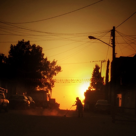 Woman sweeping street and behind beautiful sunriseの素材