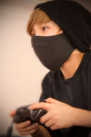 Boy playing video games, he uses protective cover mask due pandemicの写真素材