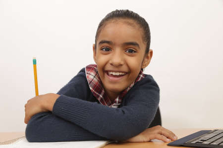 Brunette girl does homework and classes with an iPad device and smiles at camera