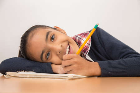 brunette girl does homework and classes writing in notebook and yellow pencilの写真素材