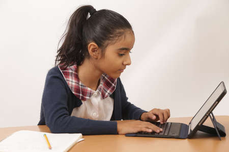 Brunette girl does homework and classes with an   device and smiles at camera