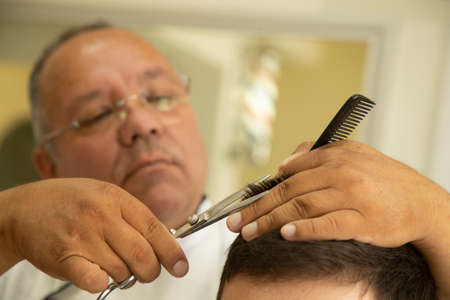 Mexican hairdresser cuts hair to teenager in a barbershopの写真素材