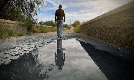 girl walking to the end of the bridge, reflection of her past in the water. Go to the futureの写真素材