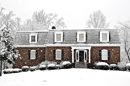 Snow falling on an executive home on a cold winter dayの写真素材