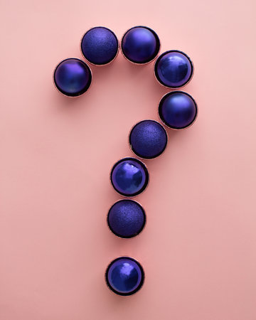 Vibrant christmas ornaments in shape of question mark on pastel pink background. Flat lay minimal design.の写真素材