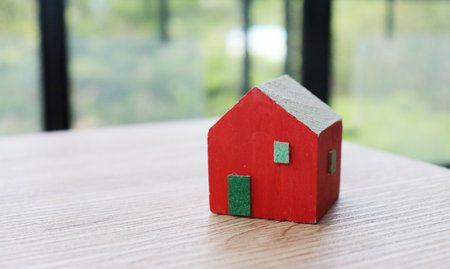 Red house model on wooden table with natural background. Real estate concept.の写真素材