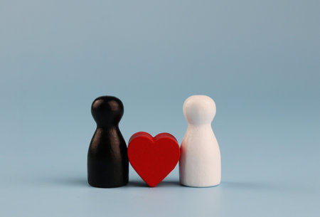 Black and white wooden figures with a red heart on a blue background.の写真素材