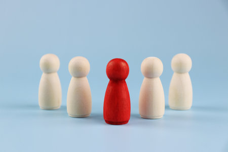 Wooden figures of people on a blue background. The concept of leadership and teamwork.
