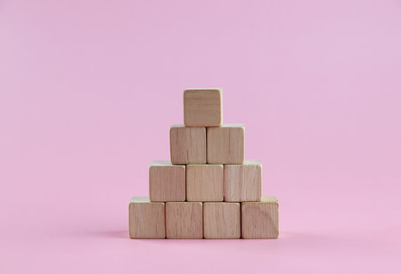 Wooden pyramid of cubes on a pink background. The concept of growth and success.の写真素材