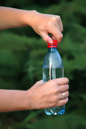 Opening a cap of a bottled mineral waterの写真素材
