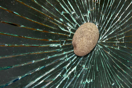 Stone hits and shatters the window glass of a house-car