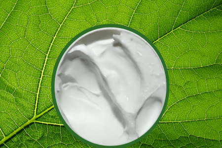 Hydra-Soothing cream on a green leaf texture of a medicinal herb, a non-greasy moisturizing milk, repairs and nourishes skinの写真素材