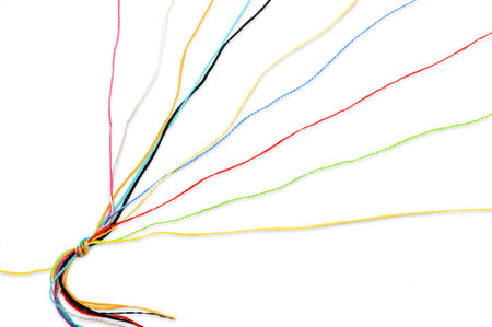 Multicolored tangled knitting threads tied in a knot on one side on a white backgroundの写真素材
