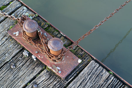 Detailed close-up of old wooden pontoon boards with rusty bolts and corroded chain, showing rustic...