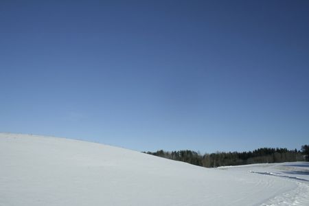A snowy hill is on a sunshine. Deep blue sky. Cloudnessの写真素材
