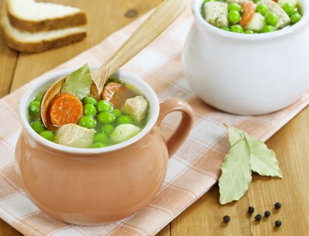 Soup with meat and green peas in the pot on the tableの写真素材