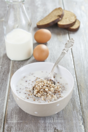 Buckwheat porridge with milk, bread and eggs on the tableの写真素材