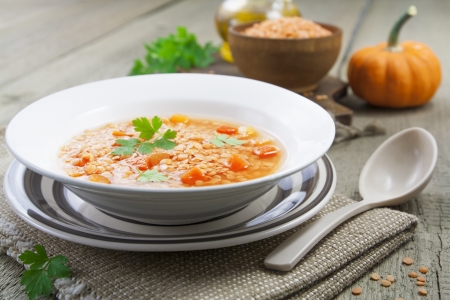 Red lentil soup with vegetables in the plate on the tableの写真素材