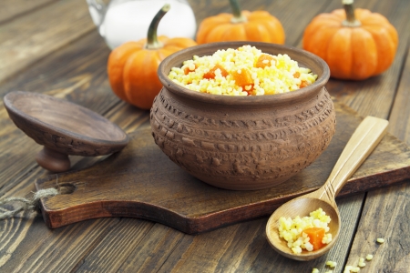 Millet porridge with pumpkin and milk in a pot on the tableの写真素材
