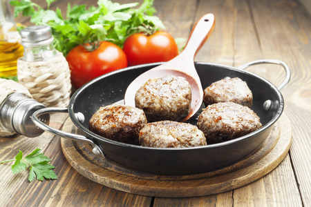 Cutlets in the pan on the wooden tableの写真素材