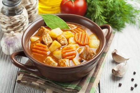 Meat with potatoes and carrots in the bowl on the table の写真素材