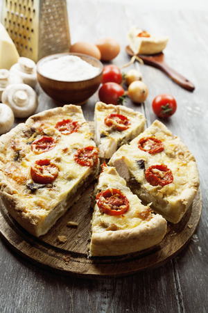 Quiche with chicken, mushrooms and cherry tomatoes on a wooden tableの写真素材
