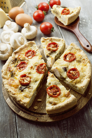 Quiche with chicken, mushrooms and cherry tomatoes on a wooden tableの写真素材