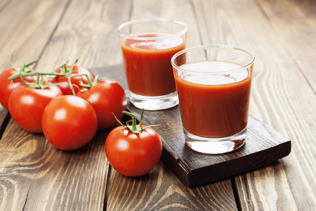 Tomato juice in a glass on a wooden tableの写真素材