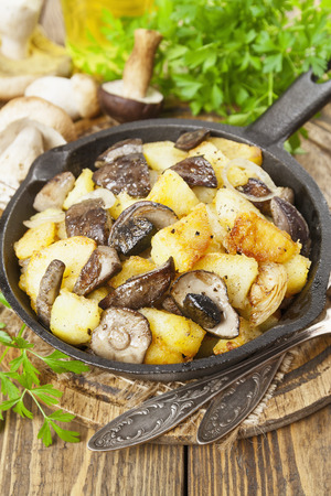 Fried potatoes with mushrooms in a frying pan on the tableの写真素材