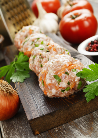 Raw meatballs with herbs on the wooden tableの写真素材